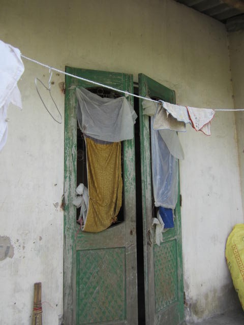 Cánh cửa chính được che bởi những tấm vải cũ, khi có mưa to thì nước mưa hắt vào tận giữa nhà
